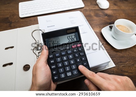 Close-up Person Hand Calculating Tax On Calculator At Desk