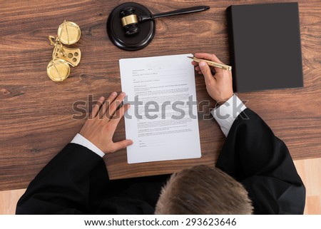Close-up Of Male Judge Reading Paper In Courtroom