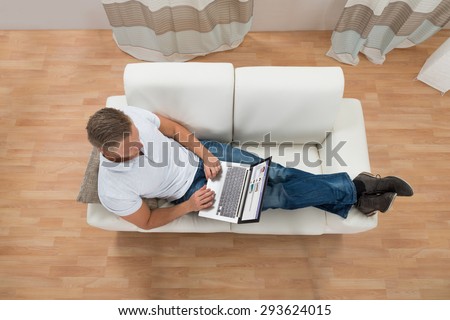Young Man On Sofa With Laptop Chatting On Social Website