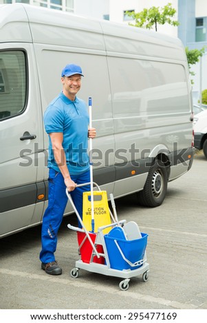 Happy Male Cleaner In Front Of Van With Cleaning Equipments