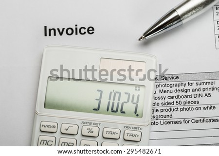 Close-up Of Pen With Calculator Over Invoice Paper