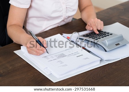 Female Accountant Calculating Bills With Calculator In Office