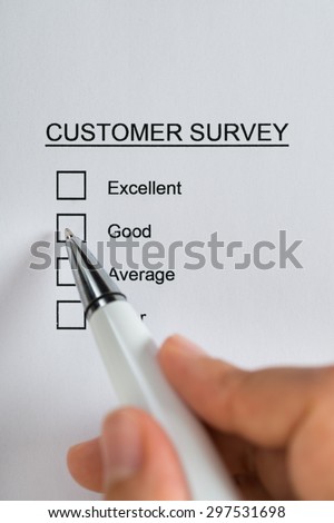 Close-up Of Person Hands Filling Customer Survey Form With Pen