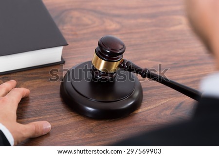 Close-up Of Judge Hitting Mallet At Wooden Desk In Courtroom