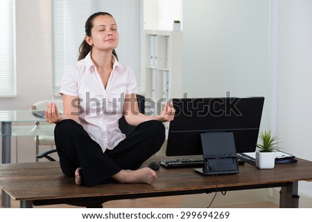 Young Businesswoman Doing Meditation On Desk In Office