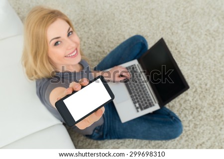 Young Beautiful Woman With Mobile Phone And Laptop Sitting On Carpet