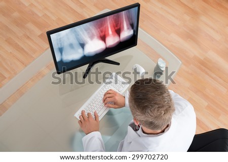 Young Male Dentist Looking At Teeth X-ray On Computer