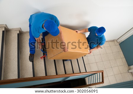 movers carrying a box on a staircase