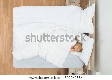 High Angle View Of Young Woman Sleeping In Bed With Blanket