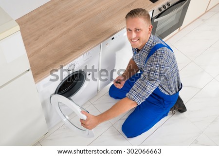 Happy Male Technician With Screwdriver Repairing Washing Machine