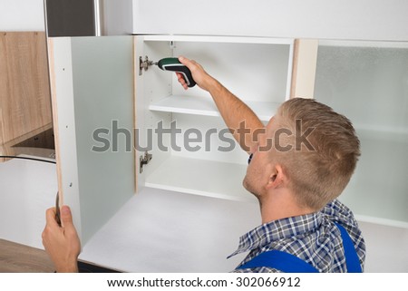 Male Carpenter Drilling In Cabinet With Electric Cordless Drill