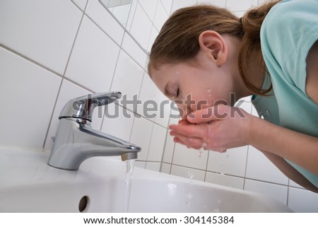 Little Girl Washing Mouth With Water In Bathroom
