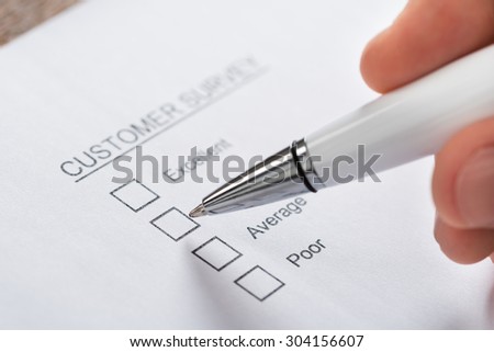 Close-up Of Person Hands With Pen Filling Customer Survey Blank Form