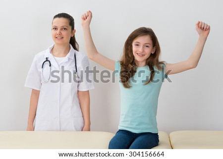 Happy Child Sitting On Bed Next To Female Doctor In Hospital