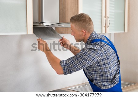 Young Repairman Repairing Kitchen Extractor Filter In Kitchen Room