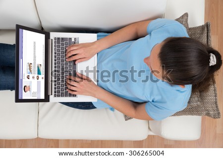 High Angle View Of Woman Chatting On Social Networking Site On Laptop