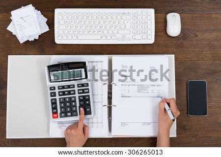 High Angle View Of Person Hands Calculating Invoice With Calculator