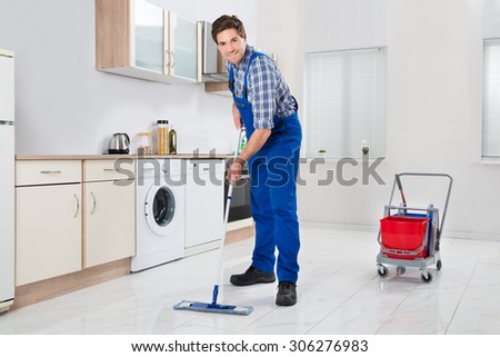Young Happy Worker In Overall Mopping Floor