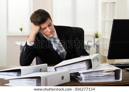 Young Stressed Businessman With Folders Working In Office