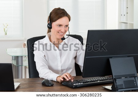 Female Customer Service Representative With Headset Working On Computer In Office