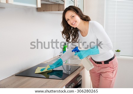 Young Woman Smiling While Cleaning Induction Hob On Countertop At Home