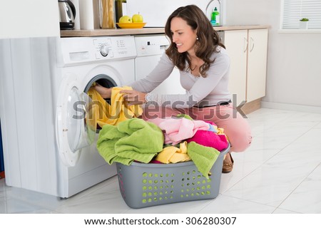 Young Woman Putting Clothes Into Washing Machine At Home
