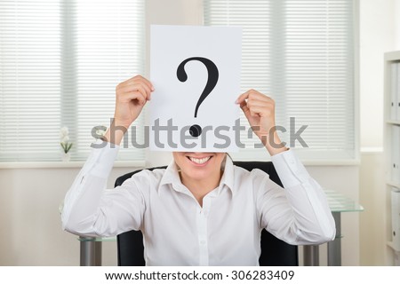 Happy Businesswoman Showing Question Mark On Paper At Desk