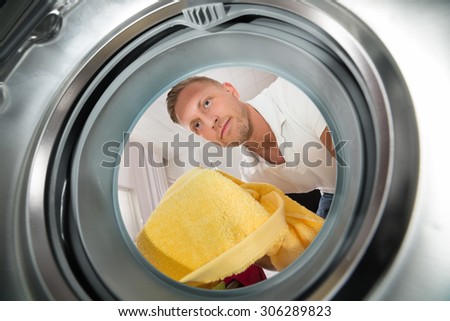 Young Man Putting Yellow Towel View From Inside The Washing Machine Appliance