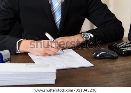 Close-up Of Businessman Signing With Pen Contract Paper At Desk