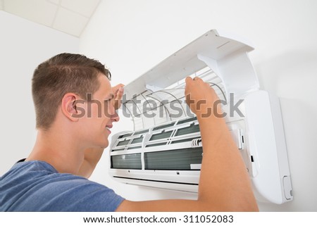 Young Happy Man Cleaning Air Conditioning System At Home