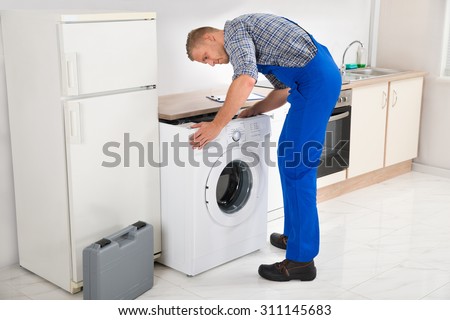 Young Man In Overall Repairing Washing Machine