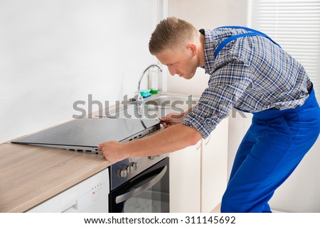 Young Repairman Installing Induction Cooker In Kitchen