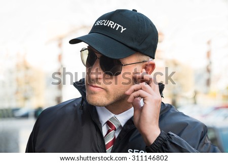 Portrait Of Young Male Security Guard Listening To Earpiece