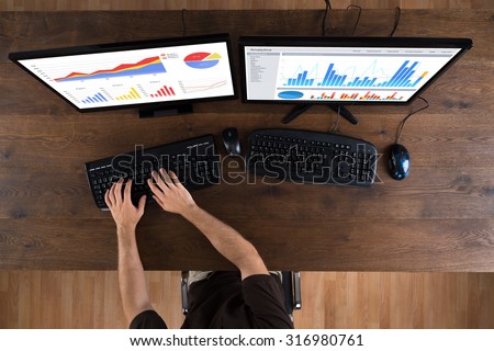 High Angle View Of Man Analyzing Graphs On Desktop Computer
