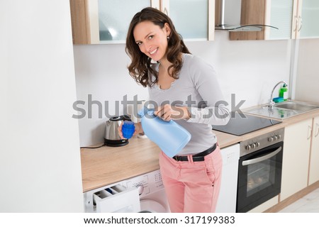 Young Happy Woman Pouring Liquid Detergent In The Bottle Cap