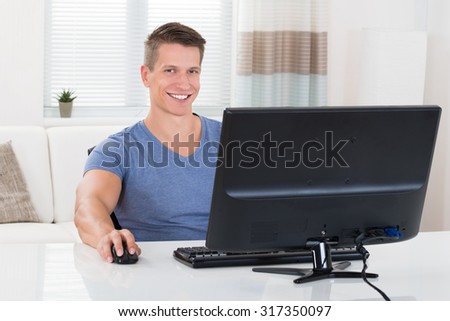Young Happy Man Using Desktop Computer In Living Room