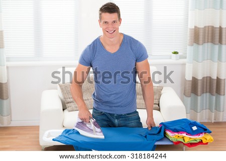 Young Happy Man Ironing Clothes On Ironing Board