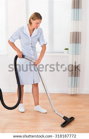 Beautiful Female Maid Cleaning Wooden Floor With Vacuum Cleaner