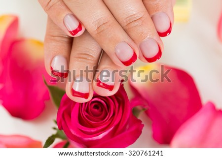 Close-up Of Hands With Manicured Nail Varnish Placed On Red Roses