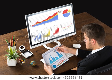 Young Businessman Analyzing Statistic Report At Desk