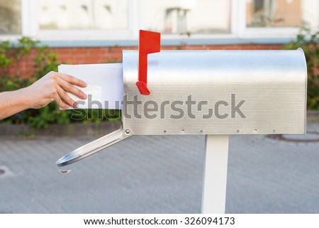 Close-up Of Person Removing Yellow Letters From Mailbox