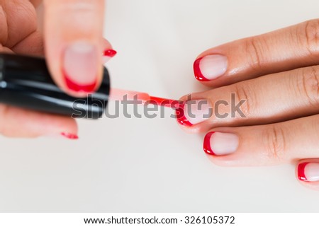 Close-up Of Female Hands Applying Red Nail Varnish