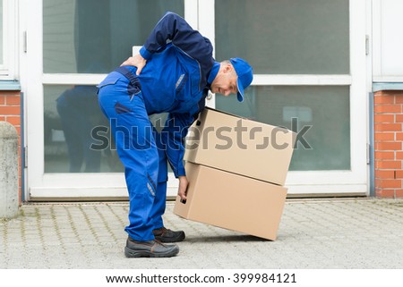 Delivery Man Suffering From Backpain While Lifting Boxes 商業照片 © 
