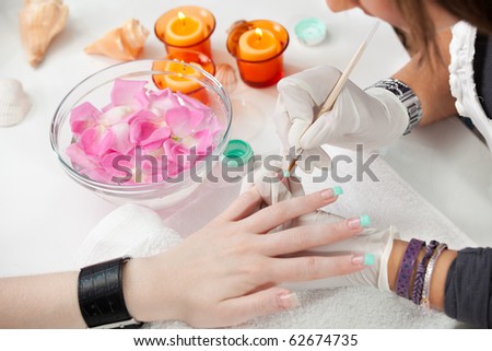 Beautician painting fingernail tips in green