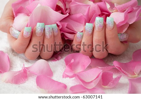 Holding pink rose petals. Artificial fingernail with airbrush pattern