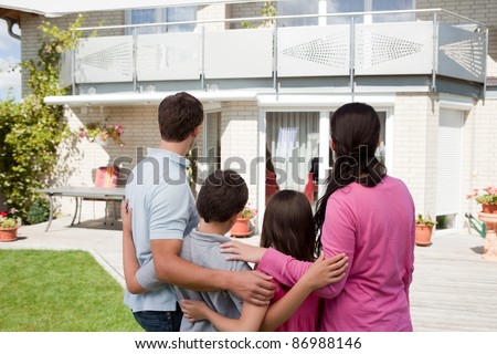 Rear view of young family standing in front of their dream home