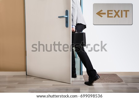 Businessperson Walking Out With Exit Sign On Wall Stock foto © 