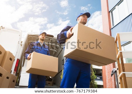 Close-up Of Two Young Delivery Men Carrying Cardboard Box In Front Of Truck ストックフォト © 