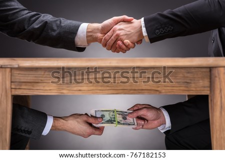 Close-up Of Two Businesspeople Shaking Hand And Taking Bribe Under Wooden Table On Grey Background 商業照片 © 