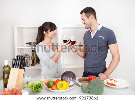 Lovely young couple cooking in the kitchen and drinking wine